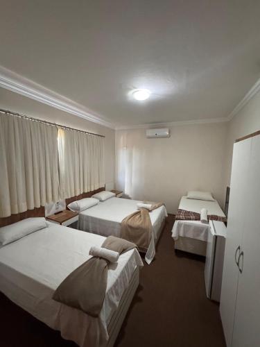 a hotel room with three beds in it at Hotel Norte Sul in Campo Grande