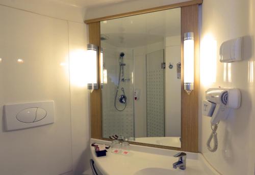 a bathroom with a sink and a shower and a mirror at Ibis Gading Serpong in Serpong