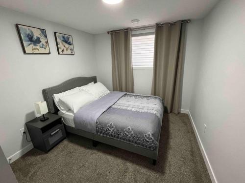 a small bedroom with a bed and a window at Charming 1Bd Basement Suite with Private Entrance in Calgary