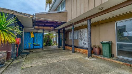 an empty hallway of a building with blue doors at Beachcomber Lodge & Backpacker in Kaitaia