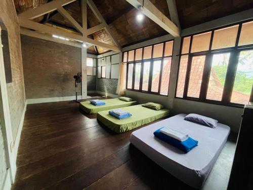 a room with two beds in it with windows at Saka Homestay Boutique & Cafe in Borobudur