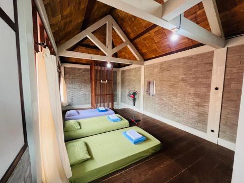 two green beds in a room with a brick wall at Saka Homestay Boutique & Cafe in Borobudur