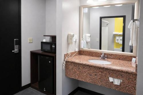 a bathroom with a sink and a mirror and a microwave at Super 8 by Wyndham Salina I-70 in Salina