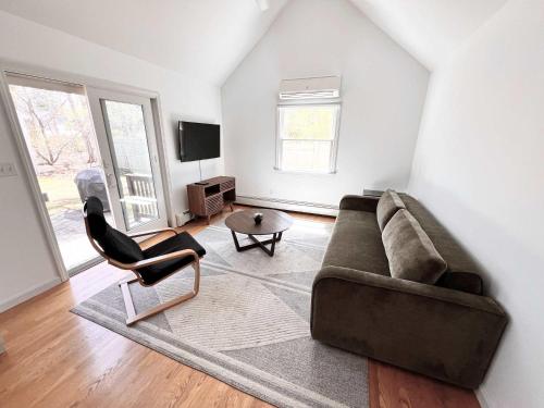 a living room with a couch and a chair at Jenkins Pond Beach Access with BBall Hoop & Grill, Bright Cape Cod Retreat near Jenkins Pond in Falmouth - Parking, Modern Retreat with Outdoor Space, 24 Hour Hospitality in Falmouth