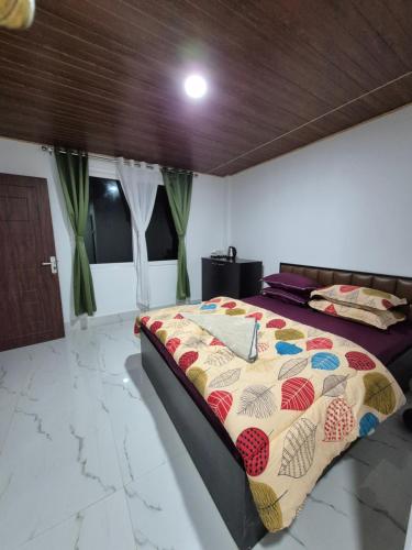 a bedroom with a bed with a quilt on it at Aadharjun Homestay in Chidām