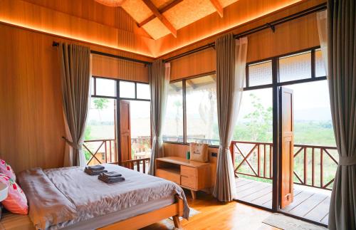 a bedroom with a bed and a balcony with windows at Baannok at Motakhian in Pak Chong