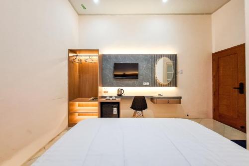 a bedroom with a large white bed and a mirror at Abbas Syariah Hotel near Menara Kudus Mitra RedDoorz in Kudus