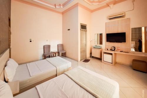 a hotel room with two beds and a television at Abbas Syariah Hotel near Menara Kudus Mitra RedDoorz in Kudus
