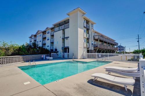 a swimming pool with two chairs and a building at Surf City Stay Motel Unit - Walk to Beach in Surf City