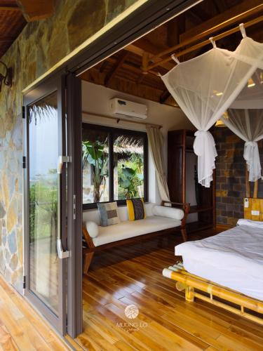 a room with a bed and a couch and windows at Mường Lò Retreat Nghia Lo in Yên Bái