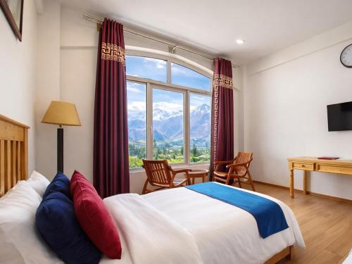 a bedroom with a bed and a large window at Hispar Hotel Skardu in Skardu