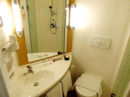 a bathroom with a sink and a toilet and a mirror at Ibis Jakarta Senen in Jakarta