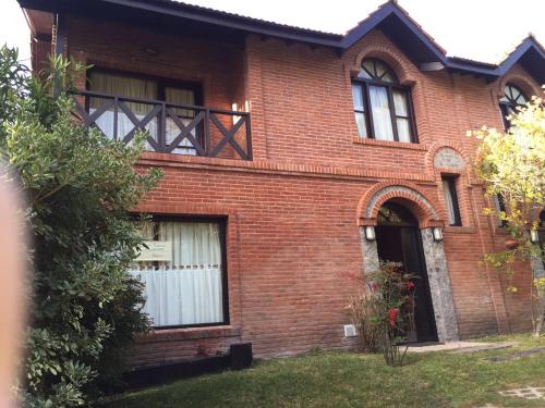 una casa de ladrillo rojo con cortinas blancas en el patio en DUPLEX Casa 100 m2 CARILO HOUSE Complejo Residencial Sin Serv en Cariló