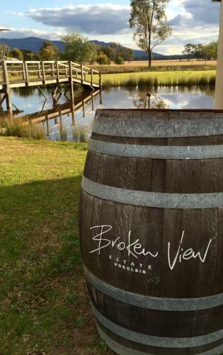 a wooden barrel sitting in the grass next to a body of water at Broken View Estate in Pokolbin
