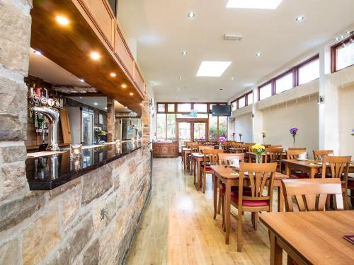 a restaurant with tables and chairs and a stone wall at Cumberland Hotel in Edinburgh