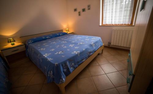 a bedroom with a bed with a blue comforter and a window at Casa al Portico in Ledro
