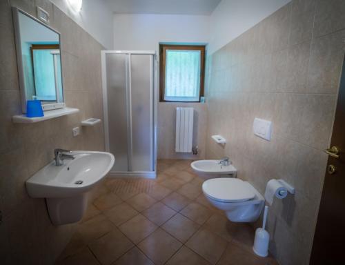 a bathroom with two sinks and a toilet and a shower at Casa al Portico in Ledro