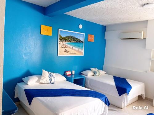 two beds in a blue room with a beach at Hotel Zihua Malibu in Zihuatanejo