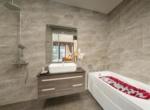 a bathroom with a tub and a sink and a mirror at ORA Hotel in Văn La