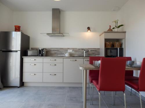 une cuisine avec des chaises rouges et une table en bois dans l'établissement Au bois flotté, à Saint-Pierre-dʼOléron