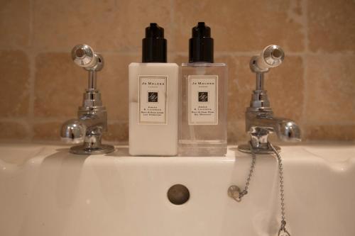 two bottles ofodorizers sitting on top of a sink at Centre village 2 bedroom cottage - The Byre in Pewsey
