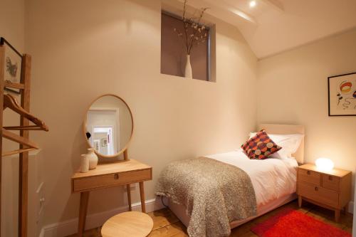 a small bedroom with a bed and a mirror at The Byre - 2 bedroom cottage in Pewsey