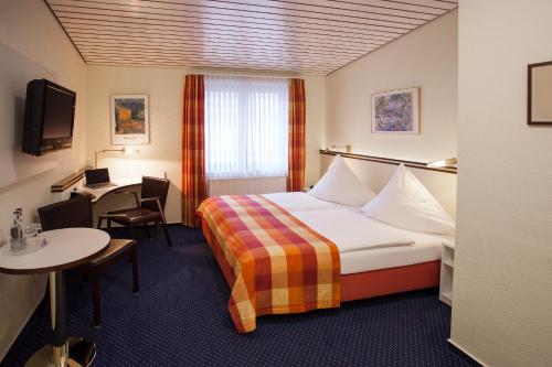 Habitación de hotel con cama y mesa en Centro Hotel Goya en Wolfsburg