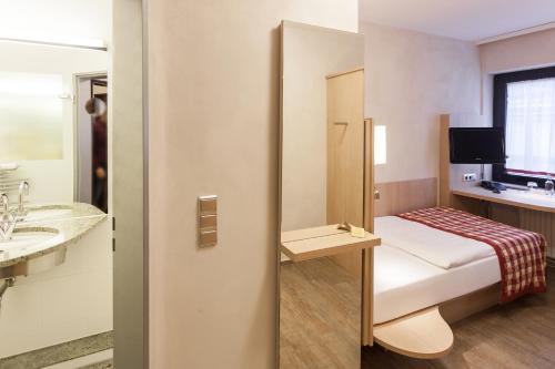 Habitación pequeña con cama y baño. en Centro Hotel Goya en Wolfsburg