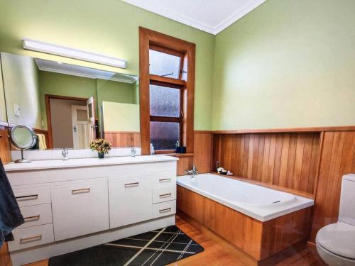 a bathroom with a tub and a sink and a mirror at School Lane Guesthouse in Whangarei