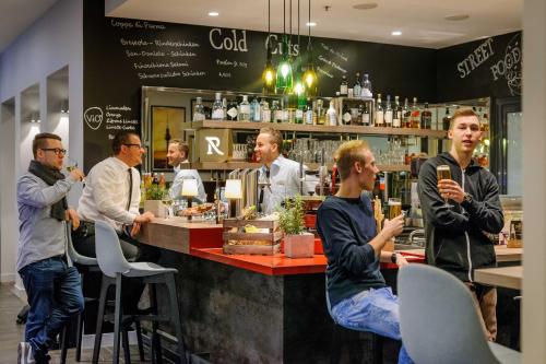 a group of men standing around a bar in a restaurant at Mercure Hotel & Residenz Berlin Checkpoint Charlie in Berlin