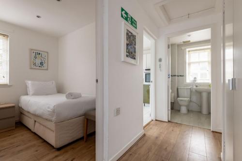 a white bedroom with a bed and a bathroom at Bangor Cottage - Elie in Elie