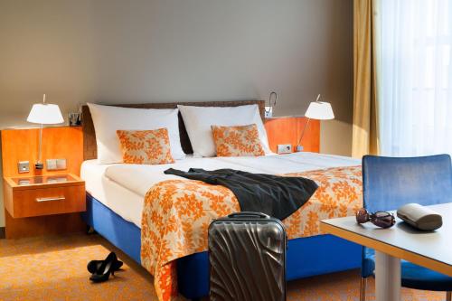a hotel room with a bed and a table and a suitcase at Mercure Hotel & Residenz Berlin Checkpoint Charlie in Berlin