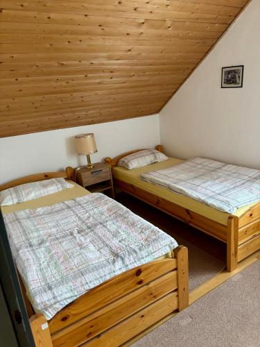 two beds in a room with wooden ceilings at Johanna Balatoni Ház in Balatonfenyves