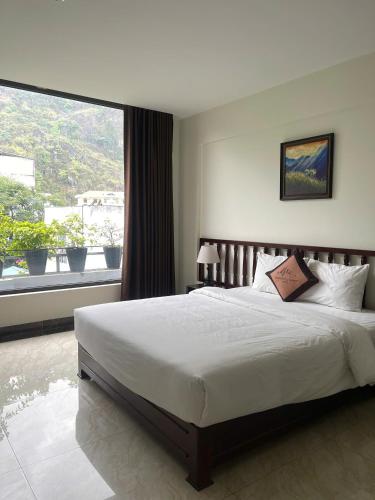 a bedroom with a large bed and a large window at Dongvan Ville Du H'Mong Hotel in Dồng Văn