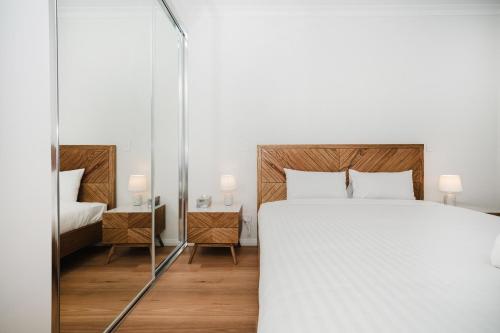 a bedroom with a large white bed and a mirror at Hello Dolphins Villas in Mandurah