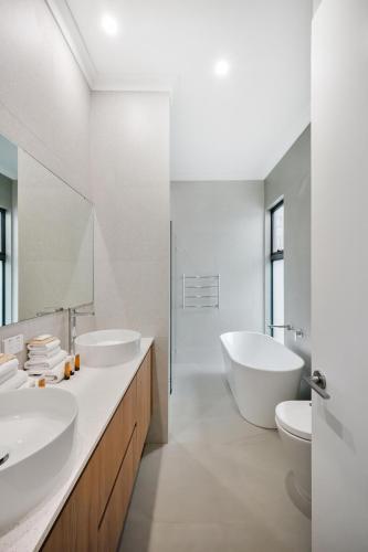 a white bathroom with two sinks and two toilets at Hello Dolphins Villas in Mandurah