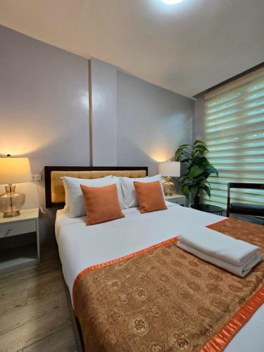 a bedroom with a large white bed with orange pillows at J Spazio Apartelle and Cafe in Baranghauon