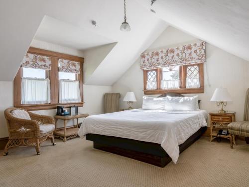 a bedroom with a large bed and two windows at Pacific Grove Inn in Pacific Grove