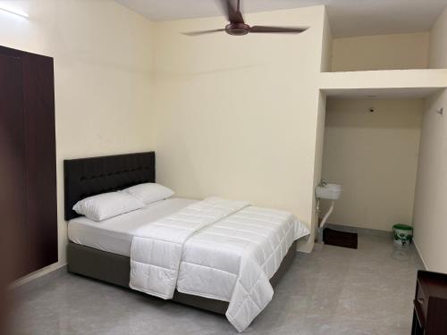 a bedroom with a bed with white sheets and a ceiling fan at Balaas Inn in Karaikal