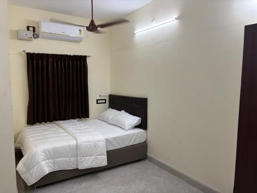 a bedroom with a bed and a ceiling fan at Balaas Inn in Karaikal