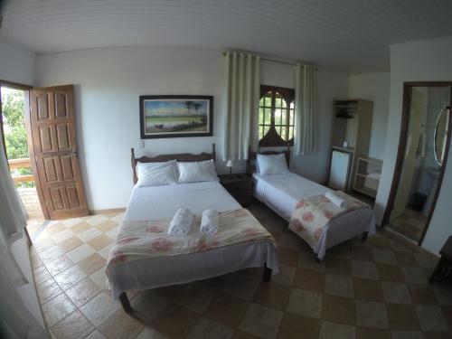 a large bedroom with two beds and a door at Pousada Santa Helena in Iriri