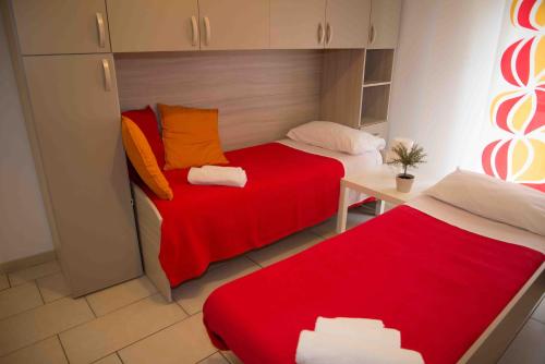 ナポリにあるCarol Houseの赤いシーツが備わる小さな部屋のベッド2台
