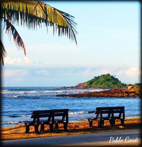 three benches sitting on a beach near the ocean at Hostel Itanhaém in Itanhaém