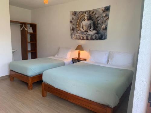 two beds in a room with a statue on the wall at Casa AmaNacer Malinalco in La Ladrillera