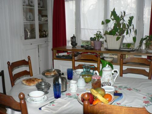 a dining room table with a white table cloth with food on it at Chambre Eugénie in Saint-Cloud