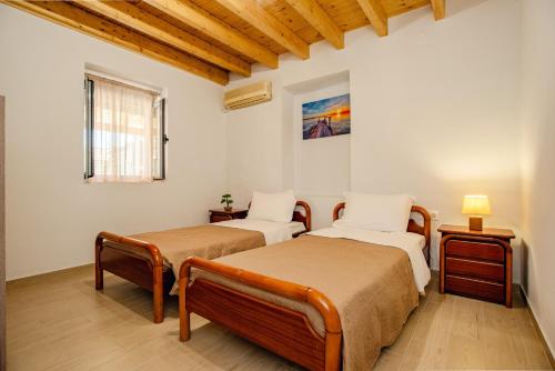two beds in a room with wooden ceilings at KOUL HOUSE in Lefkimmi