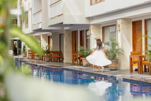 a woman in a white dress walking by a swimming pool at Bali Sun Tropical Hotel & Spa - formerly The Sun Hotel & Spa Legian in Legian