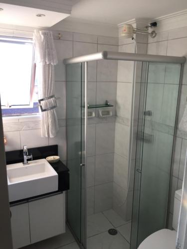 a bathroom with a glass shower and a sink at Apartamento Astúrias 2 Dorms Ar Cond in Guarujá