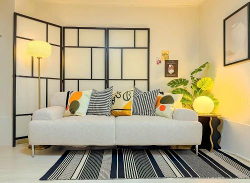 a living room with a white couch with pillows at Hongdae 10 min Family 2BR Direct Airport Bus from ICN airport in Seoul