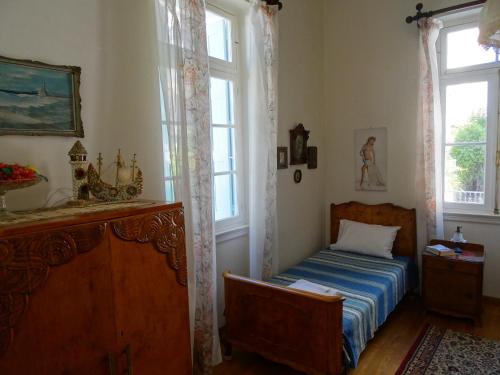 a bedroom with a bed and two windows at Neoclassical House in Chania